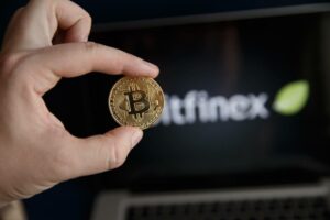 a person holding a bit coin in front of a computer