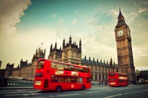 a red double decker bus driving past big ben