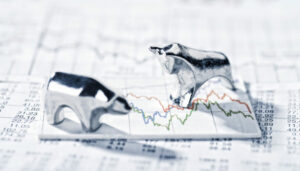 a pair of silver bull and bear figurines on top of a stock chart