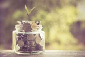 a glass jar filled with coins and a plant growing out of it