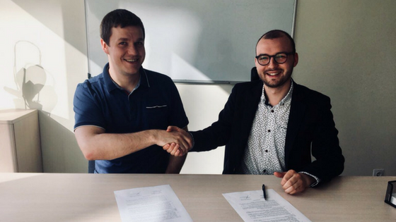 two men sitting at a table shaking hands