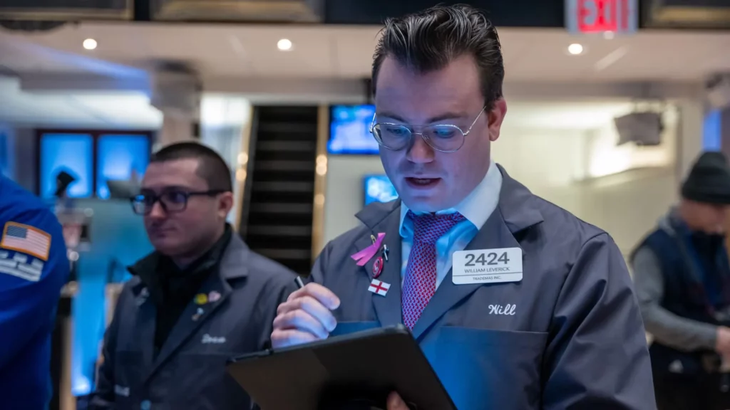 Wall Street stock trader standing holding a computer tablet device.