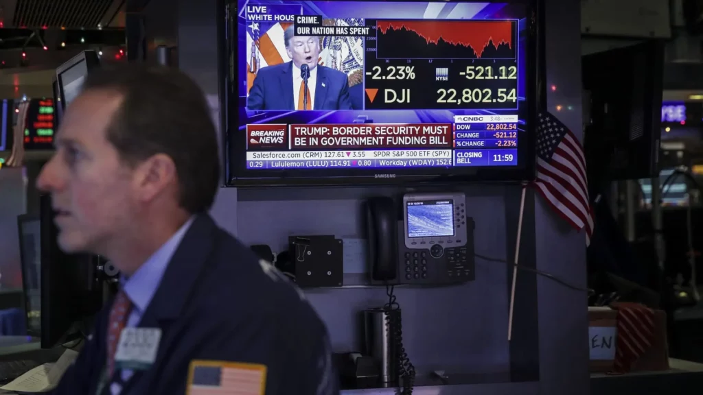 Donald Trump on TV in background of New York Stock Exchange. A trader in the foreground.