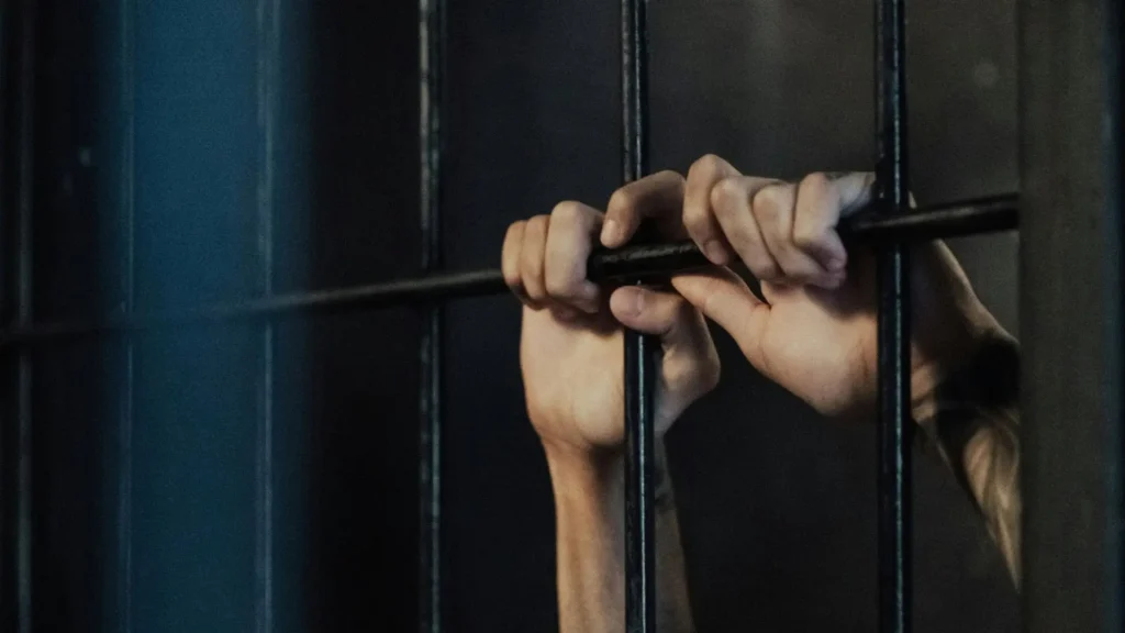 hands behind prison bars